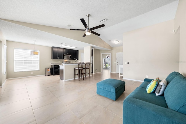 tiled living room featuring ceiling fan, lofted ceiling, and a textured ceiling