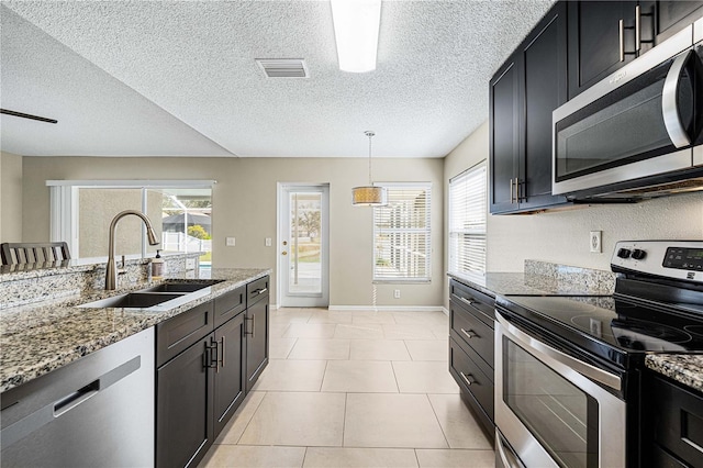 kitchen featuring pendant lighting, sink, light tile patterned floors, light stone counters, and stainless steel appliances