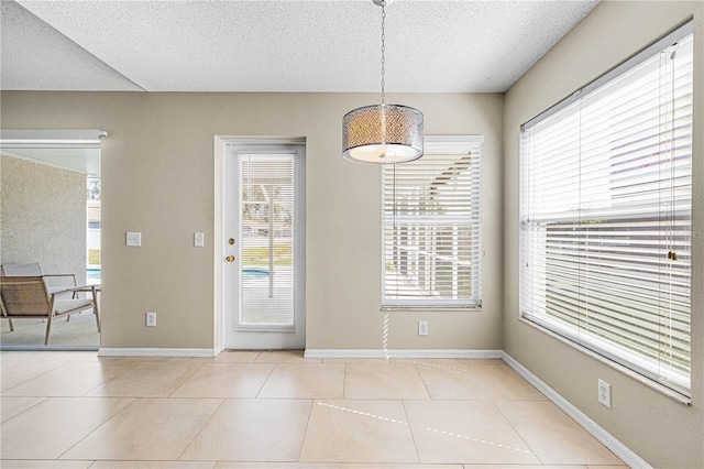 unfurnished dining area with light tile patterned floors and a textured ceiling