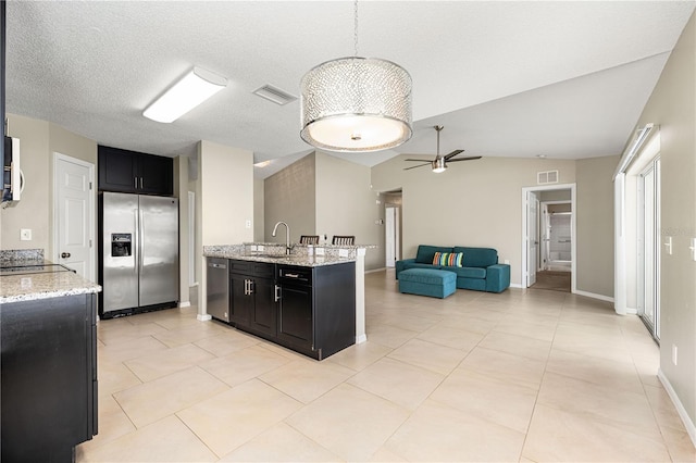 kitchen featuring light stone counters, stainless steel appliances, decorative light fixtures, and sink