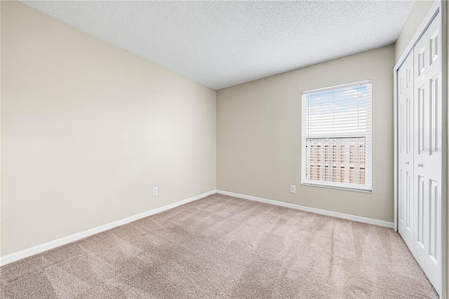 unfurnished bedroom featuring light colored carpet, a closet, and a textured ceiling