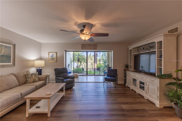 living room with baseboards, dark wood-style floors, visible vents, and ceiling fan