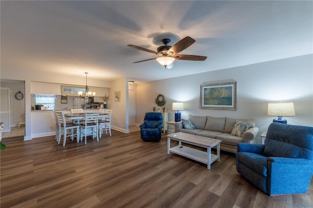 living room featuring baseboards, dark wood-style floors, and ceiling fan with notable chandelier