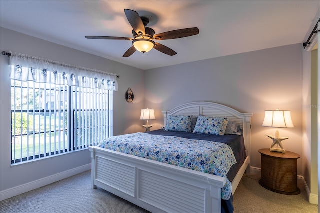 bedroom featuring a ceiling fan, a barn door, carpet, and baseboards