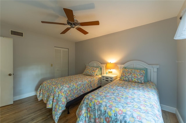 bedroom with visible vents, baseboards, wood finished floors, a closet, and a ceiling fan