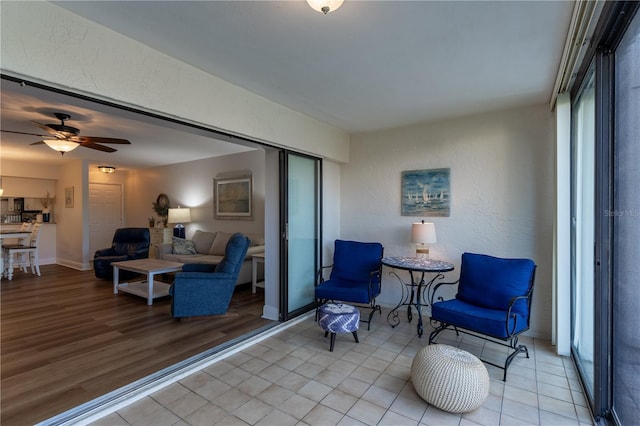 exterior space with light wood-style flooring, baseboards, ceiling fan, and a textured wall