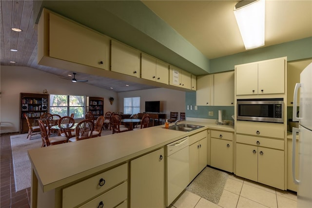 kitchen featuring cream cabinetry, a sink, stainless steel microwave, open floor plan, and dishwasher