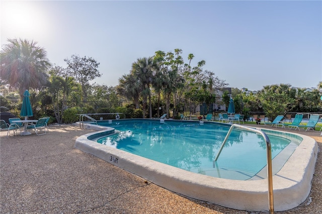 community pool with a patio and fence