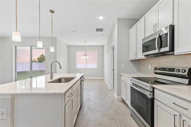 kitchen featuring appliances with stainless steel finishes, a kitchen island with sink, sink, and white cabinets