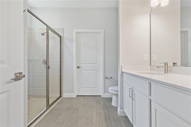 bathroom with vanity, a shower with door, and toilet