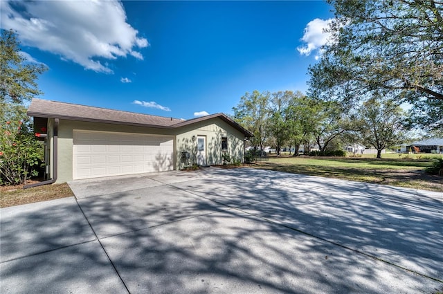 view of front of house with a garage, driveway, and stucco siding