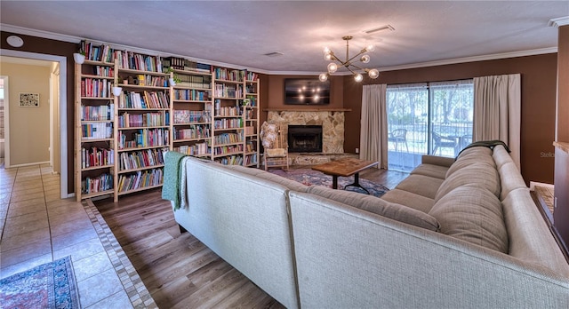 living area featuring visible vents, an inviting chandelier, tile patterned flooring, crown molding, and a fireplace