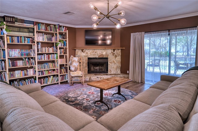 living room with a stone fireplace, a notable chandelier, wood finished floors, visible vents, and ornamental molding