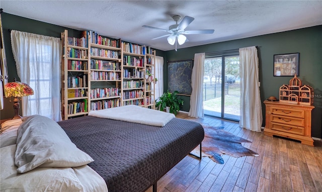 bedroom featuring access to outside, ceiling fan, a textured ceiling, and wood finished floors