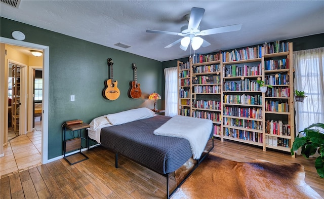 bedroom with a textured ceiling, visible vents, and wood finished floors