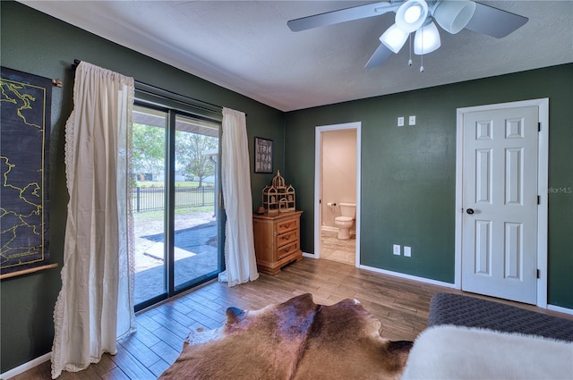 bedroom with wood finished floors, a ceiling fan, baseboards, access to exterior, and ensuite bath