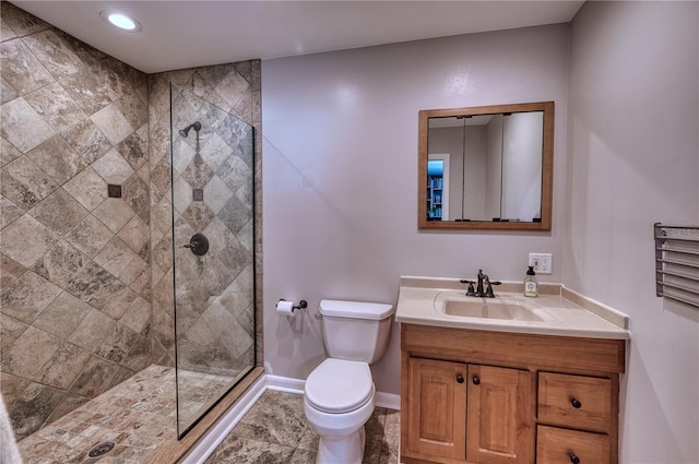 full bath with toilet, baseboards, tiled shower, and vanity