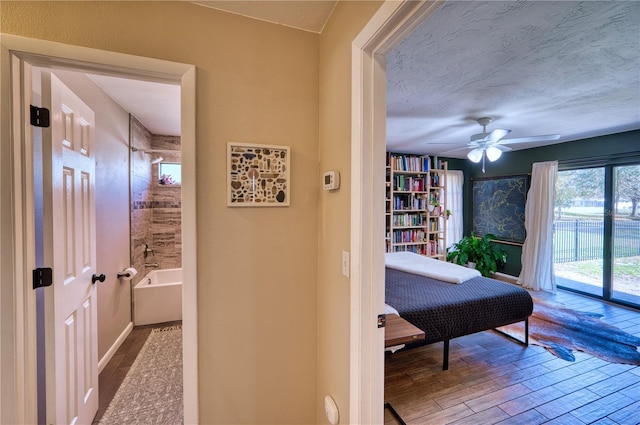 hallway featuring a textured ceiling, baseboards, and wood finished floors