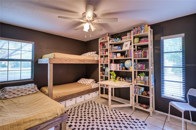 bedroom with ceiling fan, multiple windows, baseboards, and tile patterned floors