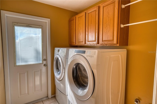 clothes washing area with light tile patterned flooring, independent washer and dryer, and cabinet space