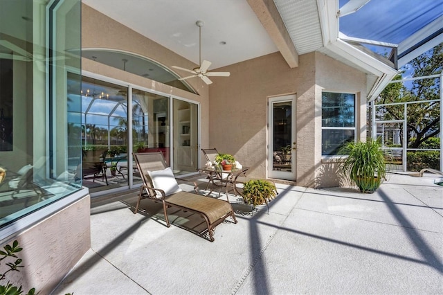 view of patio with a ceiling fan and glass enclosure