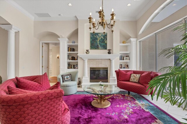 living area with ornamental molding, built in shelves, a tile fireplace, and ornate columns