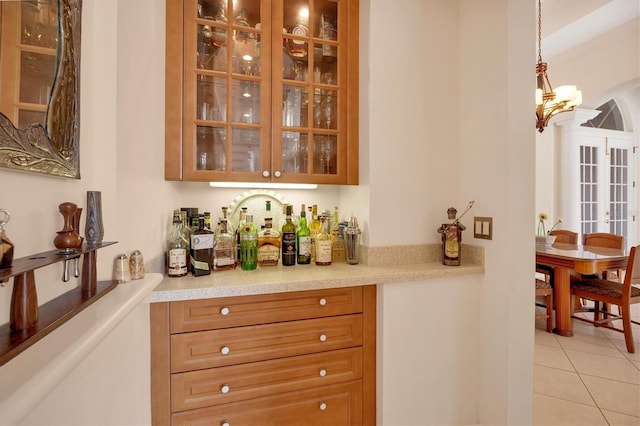 bar with french doors, a bar, a chandelier, pendant lighting, and light tile patterned flooring