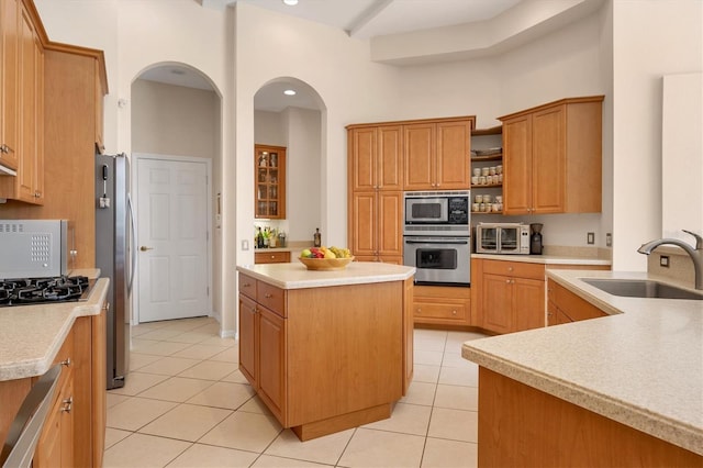 kitchen with a center island, light tile patterned floors, light countertops, appliances with stainless steel finishes, and a sink