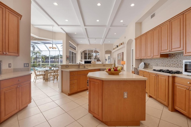 kitchen featuring visible vents, a kitchen island, a sink, black gas stovetop, and coffered ceiling