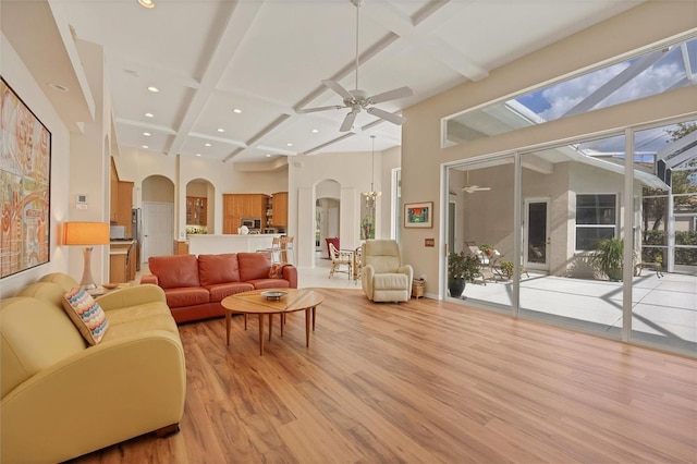 living area featuring light wood-style floors, arched walkways, coffered ceiling, and beamed ceiling