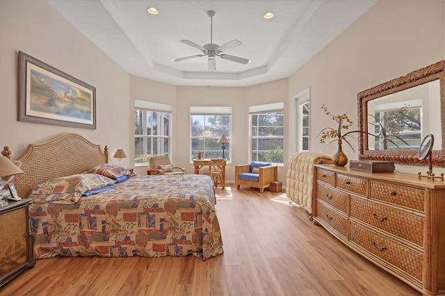 bedroom featuring ceiling fan, a tray ceiling, light wood-type flooring, and recessed lighting