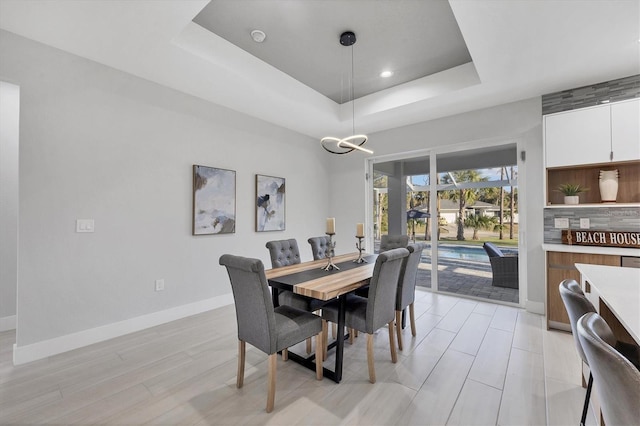 dining area with a tray ceiling and light hardwood / wood-style flooring