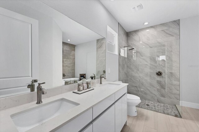 bathroom with tiled shower, vanity, and toilet