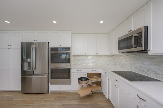 kitchen with light stone counters, tasteful backsplash, light wood-type flooring, stainless steel appliances, and white cabinets