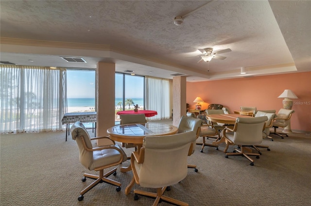 dining area with a raised ceiling, a water view, carpet flooring, and a textured ceiling