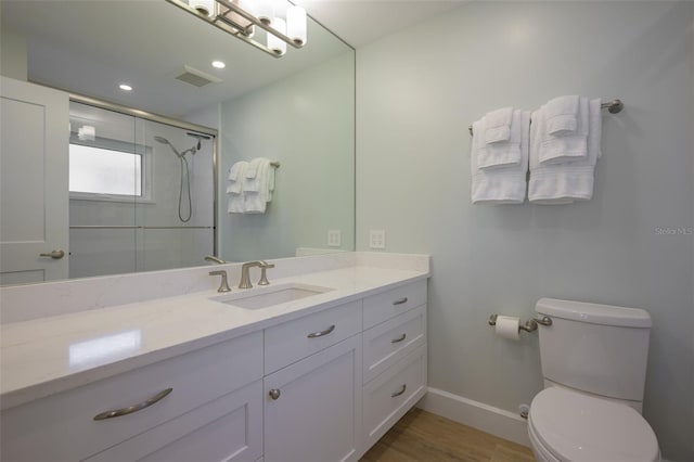 bathroom featuring vanity, wood-type flooring, an enclosed shower, and toilet