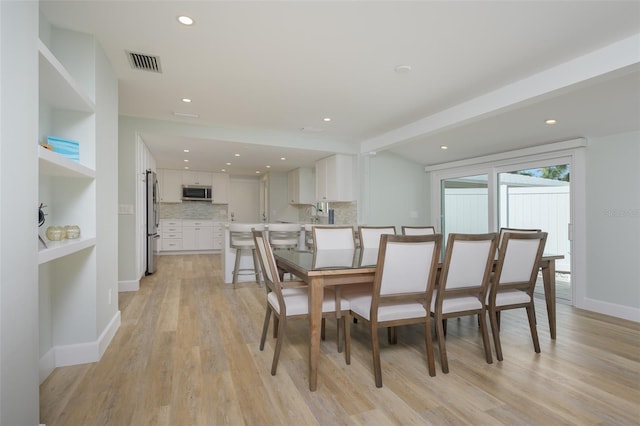 dining space with beam ceiling and light hardwood / wood-style flooring