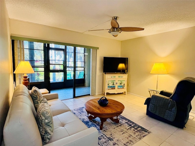 living area with light tile patterned flooring, ceiling fan, a textured ceiling, and baseboards