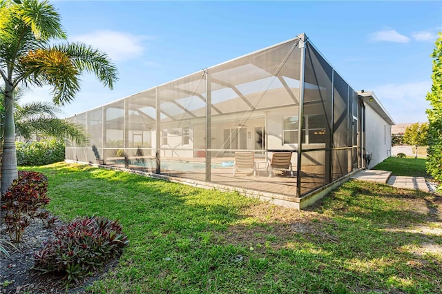 rear view of house with a patio area, a lawn, and a lanai