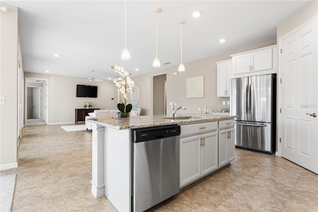 kitchen featuring appliances with stainless steel finishes, decorative light fixtures, white cabinetry, and a kitchen island with sink