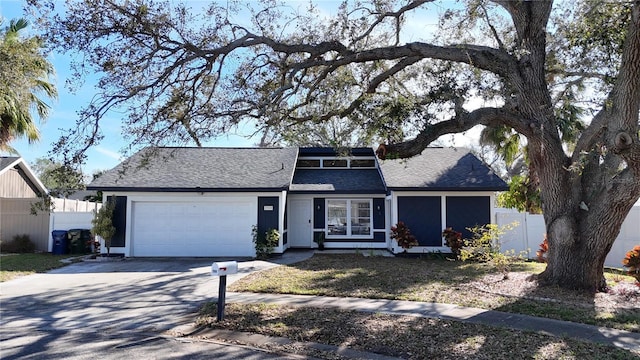 view of front of home with a garage, driveway, and fence