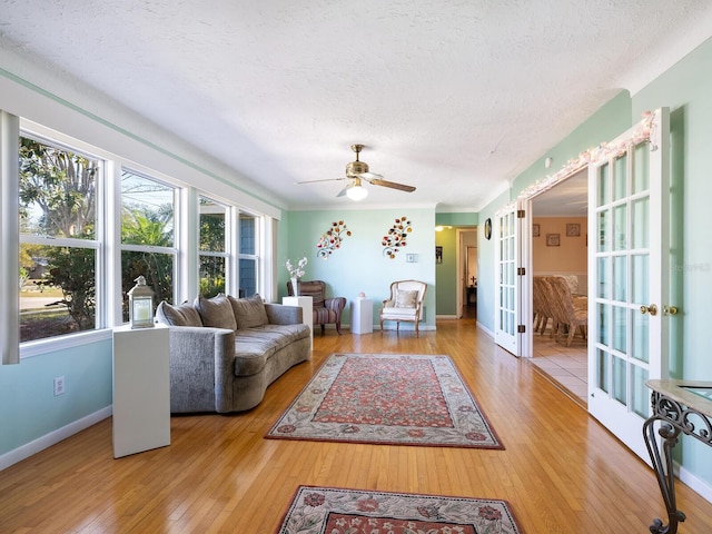 living room with hardwood / wood-style flooring, ceiling fan, french doors, and a textured ceiling