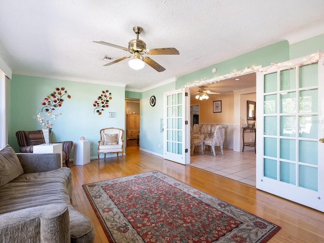 living room featuring hardwood / wood-style flooring, ceiling fan, a textured ceiling, and french doors