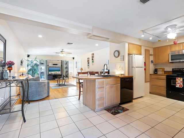 kitchen featuring light tile patterned flooring, light brown cabinetry, sink, a kitchen breakfast bar, and black appliances