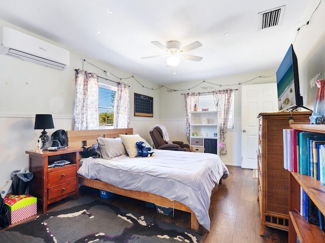 bedroom with dark hardwood / wood-style flooring, an AC wall unit, and ceiling fan