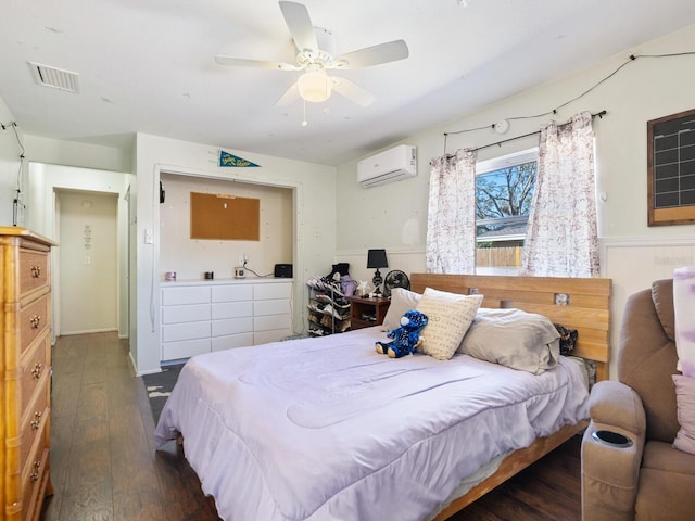 bedroom featuring ceiling fan, dark hardwood / wood-style floors, and a wall unit AC