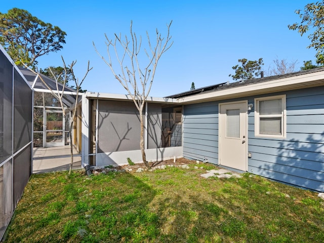 rear view of property featuring a lanai and a lawn