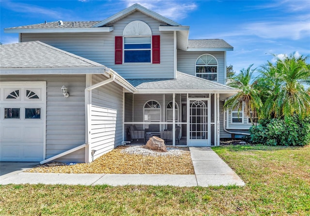 view of property with a front lawn, a garage, and a sunroom