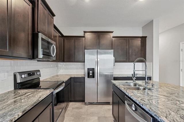 kitchen featuring appliances with stainless steel finishes, sink, backsplash, light stone counters, and dark brown cabinets