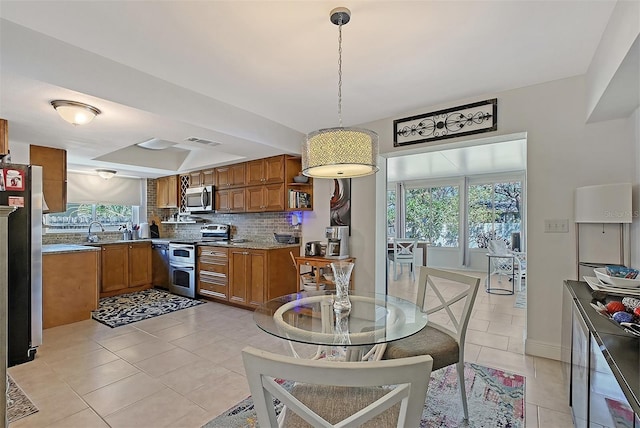 kitchen with hanging light fixtures, decorative backsplash, a wealth of natural light, and stainless steel appliances